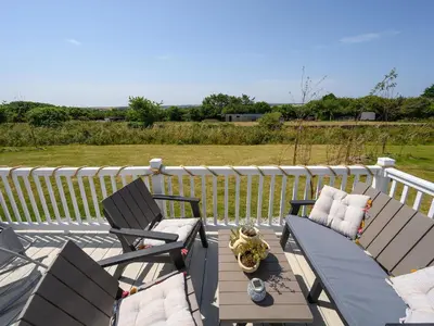two chairs and a table on a deck with a fence at Rose View in Newquay