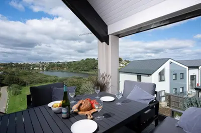 a table on a deck with a view of a river at Swanpool View - Walk to Beach - Free WiFi & Parking - Sea & Lake Views in Falmouth
