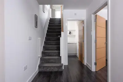 a staircase in a home with white walls and wooden floors at Swanpool View - Walk to Beach - Free WiFi & Parking - Sea & Lake Views in Falmouth