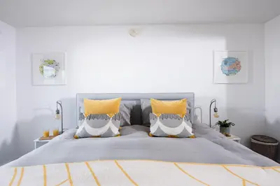 a bedroom with a large bed with yellow pillows at Swanpool View - Walk to Beach - Free WiFi & Parking - Sea & Lake Views in Falmouth