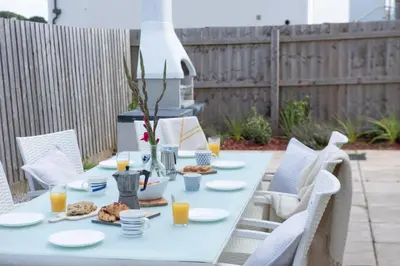 a white table with plates of food and orange juice at Swanpool View - Walk to Beach - Free WiFi & Parking - Sea & Lake Views in Falmouth