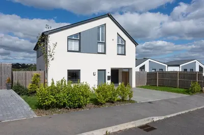 a white house with a fence at Swanpool View - Walk to Beach - Free WiFi & Parking - Sea & Lake Views in Falmouth