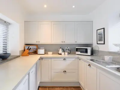 a white kitchen with white cabinets and a microwave at Finest Retreats - West Cottage at Goldsithney in Perranuthnoe