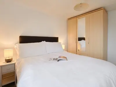 a bedroom with a large white bed and a cabinet at Finest Retreats - West Cottage at Goldsithney in Perranuthnoe