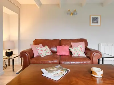 a brown leather couch with pink and pink pillows on it at Finest Retreats - West Cottage at Goldsithney in Perranuthnoe
