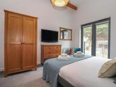 a bedroom with a bed with a dresser and a tv at Tolcarne in Truro
