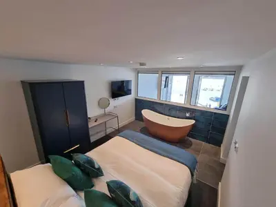 a bathroom with a tub and a bed and a bath tub at Chy Mor Apartment 1 in St Ives