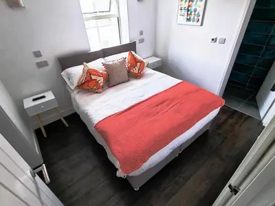 a bedroom with a bed with a red blanket and pillows at Chy Mor Apartment 1 in St Ives