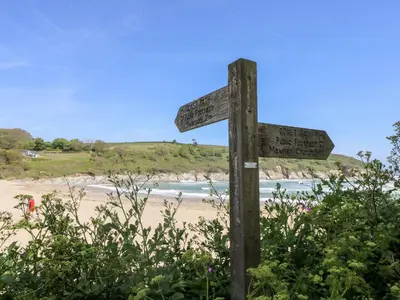 a wooden sign on a beach with the ocean at The Reading Room in Falmouth