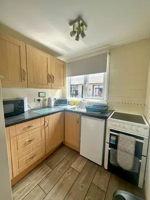 a kitchen with wooden cabinets and a white dishwasher at Charming & Spacious Holiday Home in Hayle