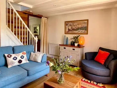 a living room with a blue couch and a chair at Unique Retreat - 2 bedroom cliff top cottage with large terrace in Portloe