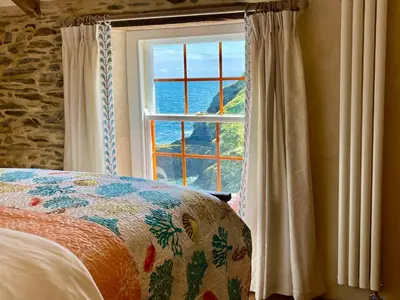 a bedroom with a window with a view of the ocean at Unique Retreat - 2 bedroom cliff top cottage with large terrace in Portloe