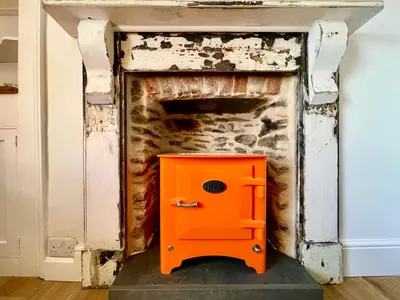 an orange box in front of a stone fireplace at Unique Retreat - 2 bedroom cliff top cottage with large terrace in Portloe