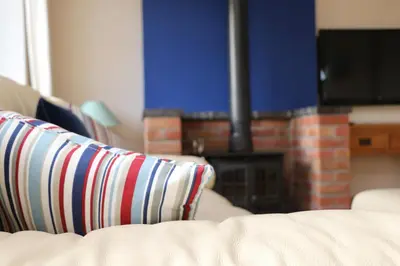 a couch with striped pillows in a living room with a fireplace at Holiday Bungalow, short drive to 7 Beaches! in St Merryn