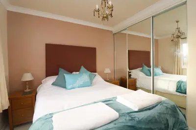 a bedroom with a large bed and a mirror at Holiday Bungalow, short drive to 7 Beaches! in St Merryn