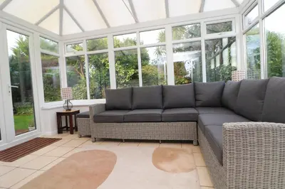 a living room with a couch in a conservatory at Holiday Bungalow, short drive to 7 Beaches! in St Merryn