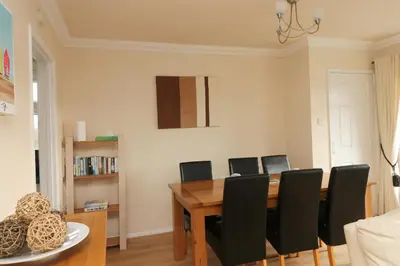 a dining room with a wooden table and black chairs at Holiday Bungalow, short drive to 7 Beaches! in St Merryn