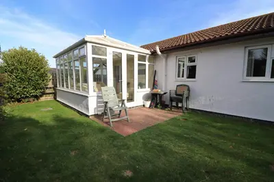 a house with a conservatory with a table and chairs at Holiday Bungalow, short drive to 7 Beaches! in St Merryn