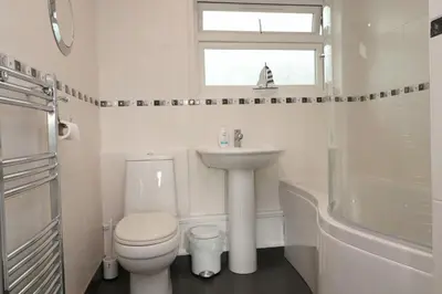 a white bathroom with a sink and a toilet at Holiday Bungalow, short drive to 7 Beaches! in St Merryn