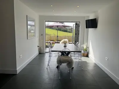 a dining room with a table and an umbrella at Elmwood in Wadebridge