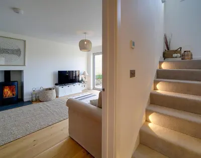 a living room with a staircase and a fireplace at Elmwood in Wadebridge