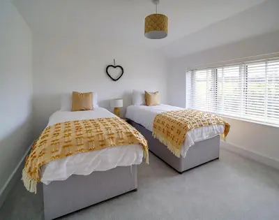 a bedroom with two beds and a heart clock on the wall at Elmwood in Wadebridge