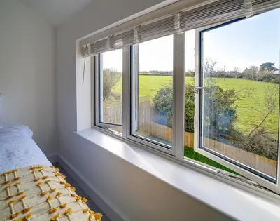 a bedroom with two windows with a view of a field at Elmwood in Wadebridge