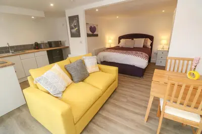a living room with a yellow couch and a bed at Perran Pearl B in Perranporth