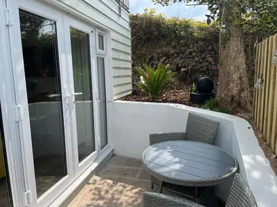 a patio with a table and chairs on a porch at Perran Pearl B in Perranporth