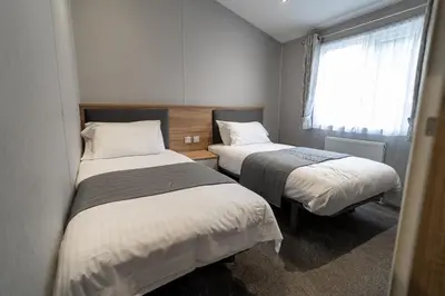 a small room with two beds and a window at ELITE BLUE LUXURY 3 BEDROOM LODGE NEWQUAY, CORNWALL in Newquay