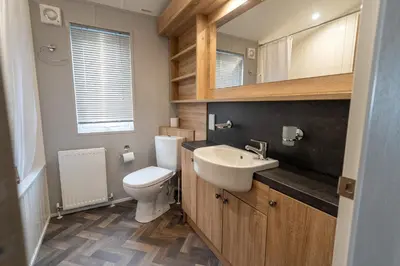 a bathroom with a toilet and a sink and a mirror at ELITE BLUE LUXURY 3 BEDROOM LODGE NEWQUAY, CORNWALL in Newquay