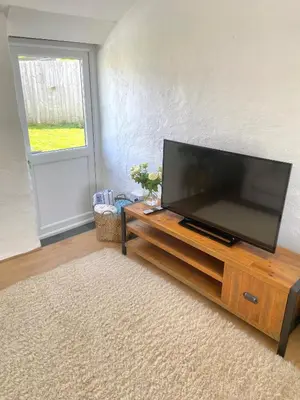 a flat screen tv sitting on top of a wooden entertainment center at Idyllic Cornish Cottage, Superking bed, private garden dogs welcome in Truro