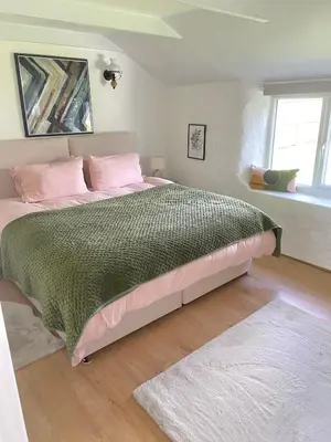 a bedroom with a large bed with pink and green sheets at Idyllic Cornish Cottage, Superking bed, private garden dogs welcome in Truro