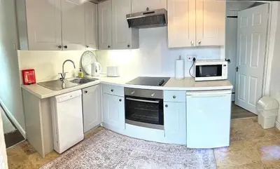 a kitchen with white cabinets and a sink and a microwave at Romantic log-burner Cornish Cottage private garden dogs welcome in Truro
