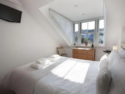 a white bedroom with a large white bed with white pillows at Alfred Wallis in St Ives