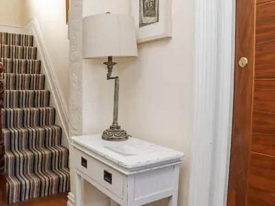 a lamp on a white table next to a staircase at Heron in St Ives