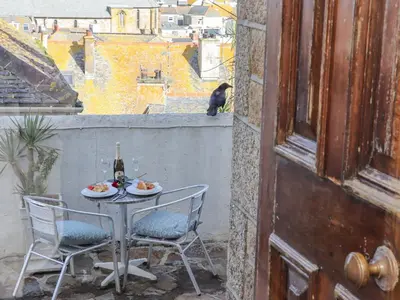 a table with two chairs and a cat sitting on a balcony at Heron in St Ives