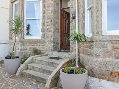 a stone house with two potted plants on the stairs at Heron in St Ives