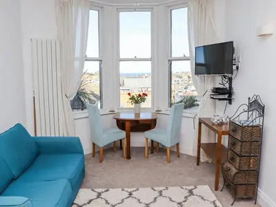 a living room with a blue couch and a table at Heron in St Ives