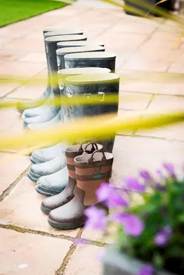 a row of rubber boots lined up on a sidewalk at Herons House Sleeps 12, heated Pool, hot tub, sauna, games room 5 Star! in Saint Columb Major