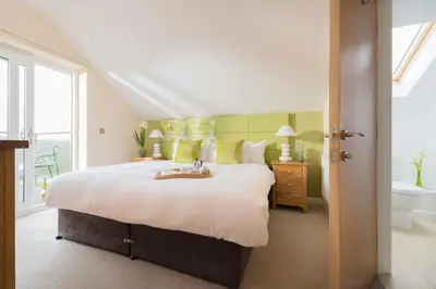 a bedroom with a bed with a sink and a tub at PointBreak Sleeps 12 with hot tub-Great celebration house-Dog friendly in Padstow