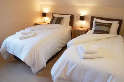 a bedroom with two beds with white sheets and two lamps at Puffin Hot tub Lodge, 4 bedrooms Resort, Pool,Gym,Bar in Padstow