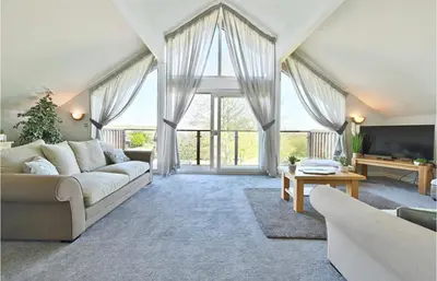 a living room with a couch and a large window at Puffin Hot tub Lodge, 4 bedrooms Resort, Pool,Gym,Bar in Padstow
