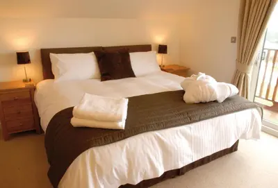 a bedroom with a large bed with towels on it at Puffin Hot tub Lodge, 4 bedrooms Resort, Pool,Gym,Bar in Padstow