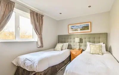 two beds in a bedroom with a window at Swallow Lodge with Hot Tub, dogs welcome sleeps 8, Great resort Facilities in Padstow
