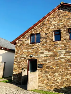 a brick building with a door on the side of it at Waveside-Waterside with hot tubResort PoolGym in Padstow