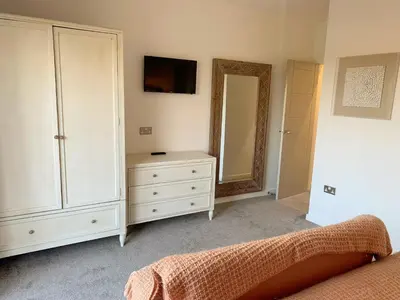 a bedroom with a white dresser and a mirror at Waveside-Waterside with hot tubResort PoolGym in Padstow
