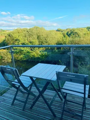 a picnic table and two chairs on a deck at Waveside-Waterside with hot tubResort PoolGym in Padstow