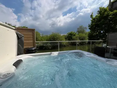 a large hot tub in a backyard with a fence at Waveside-Waterside with hot tubResort PoolGym in Padstow