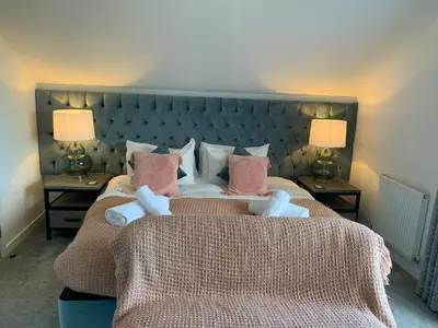 a bedroom with a large bed with two lamps at Waveside-Waterside with hot tubResort PoolGym in Padstow